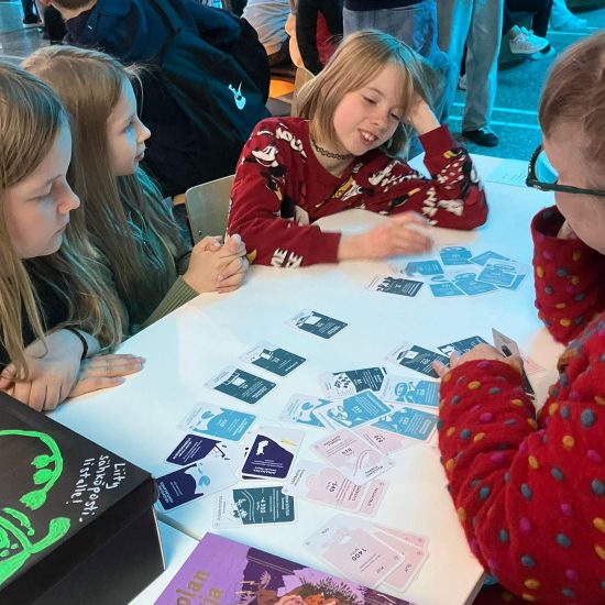 Beteendepsykolog Sinikka Hynninen-Otva spelar Klimatkoll (Ilmastotietäjä) med elever under Sci Fest-mässan i Joensuu, maj 2025.